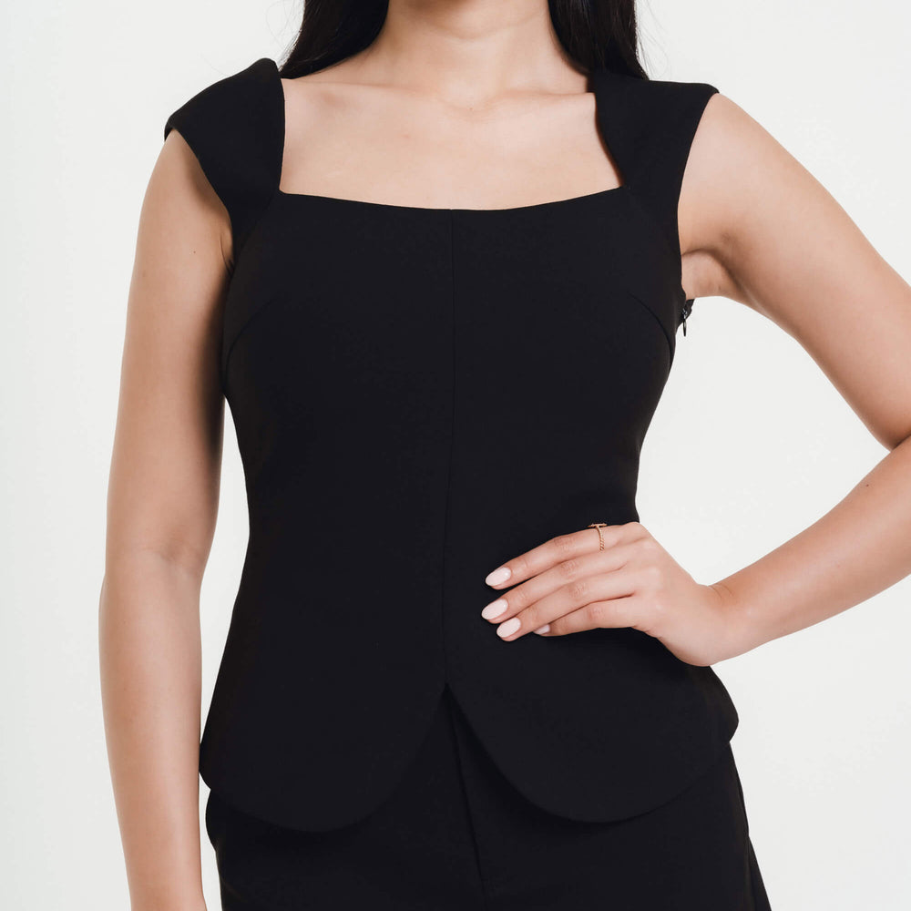 Fleur Elize black square-neck peplum top close-up — elegant structured boutique design photographed in minimalist studio light