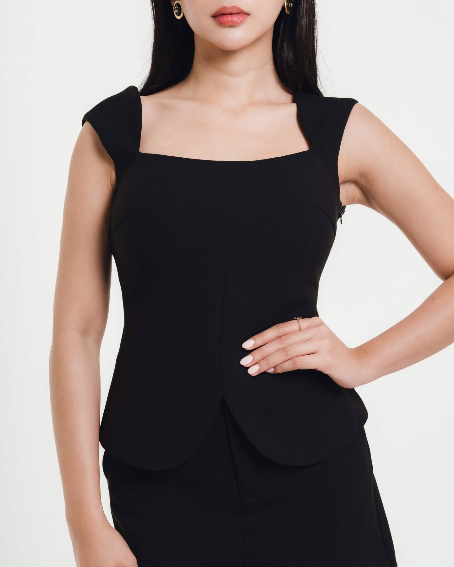Fleur Elize black square-neck peplum top close-up — elegant structured boutique design photographed in minimalist studio light